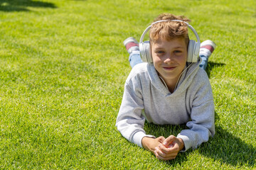 A boy relaxing on grass, listening to music - 755400607