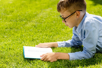 A boy reading a book on a grass - 755400888