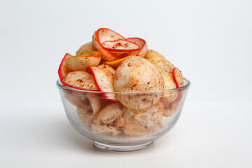 Kerupuk seblak, is colorful round crackers with spicy chili powder topping. In transparent glass bowl, isolated on white background