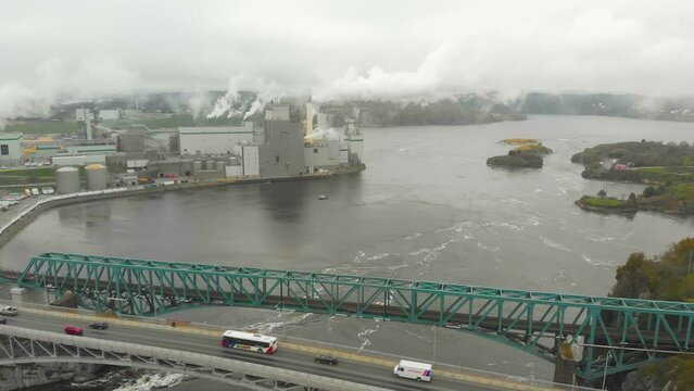 A wide Aerial shot of the Irving Pulp and Paper plant in the reversing falls with a large bridge next to it.
