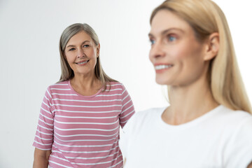 Blonde cute woman smiling nicely, her mom standing behind