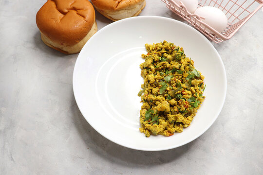 Anda Masala Bhurji or Spicy Indian scrambled eggs with bread or Bun Pav, a popular street food in Mumbai. Served in a white plate along with copy space. egg bhurji or parasi akuri. with jowar bhakri.