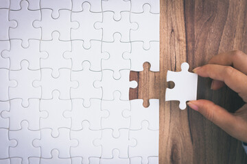 Closeup hand of woman connecting jigsaw puzzle. Business solutions, success and strategy concept.
