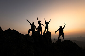 Silhouettes of a group of successful climbers on the top of a mountain.  Successfully achieving...