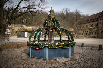 Ein mittelalterlicher Dorfbrunnen mit einer für Ostern geschmückten Überkronung