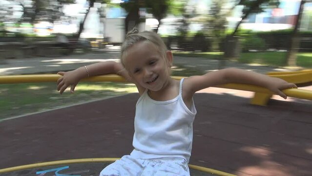 Kid Playing at Playground, Child Spinning, Rotating on Merry-Go-Round in Park, Face of Happy Girl Plays Outdoor in Nature