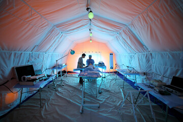 Medical worker and a student near the lying dummy inside the tent in a field hospital