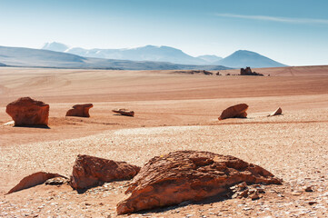 Rocks in the desert with red sand in Altiplano plateau, Bolivia. View of the volcanoes and the blue sky.