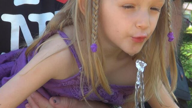 Father Help Child Drinking Water from a Fountain in Park, Playing Children