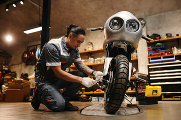 Smiling repairman changing tires of motorcycle