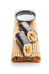 Two Sushi Rolls and Bowl of soy sauce on Bamboo Mat