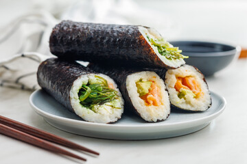 Sushi rolls on Plate with bowl of soy sauce and chopsticks.