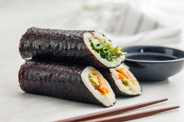 Sushi rolls on Plate with bowl of soy sauce and chopsticks.
