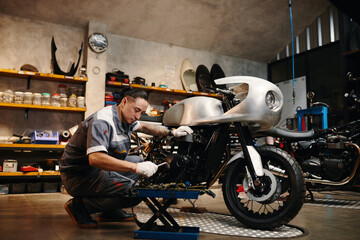 Repairman choosing tool when fixing motorcycle in his repairshop - obrazy, fototapety, plakaty