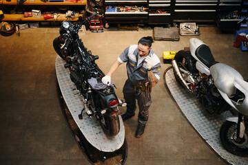 Obraz na płótnie Canvas Repairman calling motorcycle owner to discuss price of work