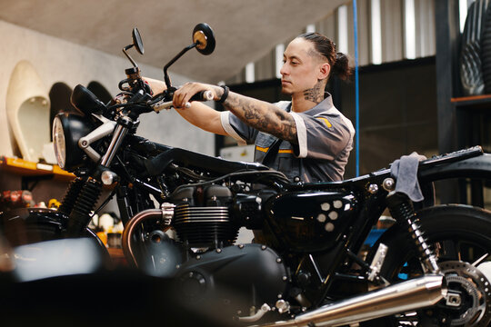 Repairman setting motorcycle handlebar when working in garage - Powered by Adobe
