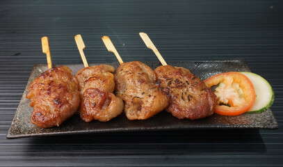 thai bbq grilled tender pork chop meat with sauce in plate on dark grey wood table asian dim sum...