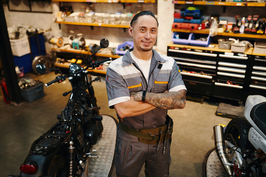 Portrait of smiling repairman working in motorcycle garage