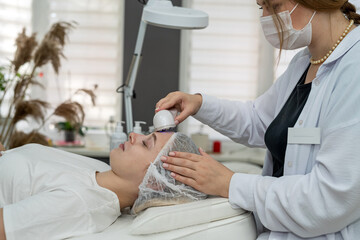 beautician doing ultrasound facial peeling cleansing lifting to rejuvenate skin by female client