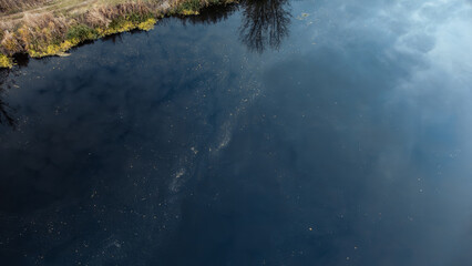 Aerial look down view on river blue reflective water surface with green reeds on riverbanks