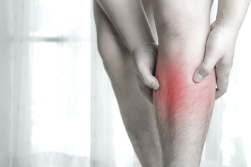 Shin injury. Male hand holding front leg with shin pain. Concept of health care, exercise-induced...