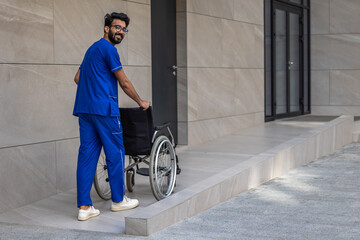 Tall dark-haired man in hospitals yard carrying a wheelchair