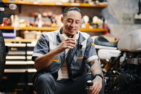 Portrait of smiling mechanic drinking coffee from thermos during break - Powered by Adobe