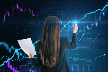 Back view of young european businesswoman with document using creative glowing candlestick forex...