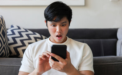 close up young teenager asian man shock feeling while using smartphone to reading about fake news...