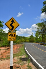 The asphalt road with a speed limit sign at 40 km/h and a curve warning sign in Tub-Lan National Park, Thailand
