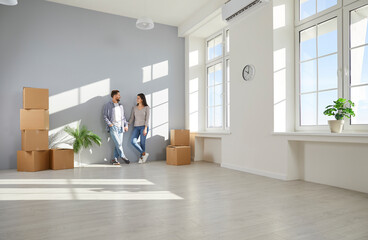Young family couple moving into a good new house or apartment. Happy man and woman homeowners...