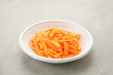 Fresh organic slice carrots on white plate grey background.
