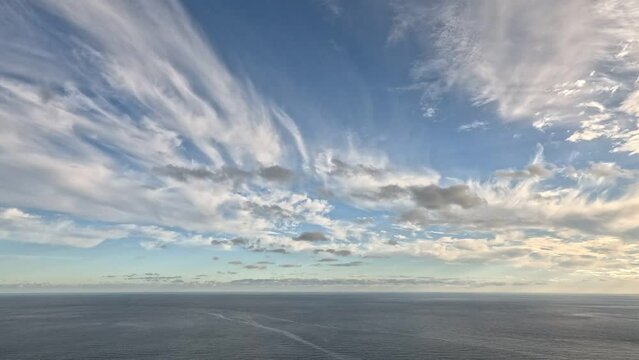 Timelapse multilayered Cirrus and Cumulus clouds moving in bright sunset sky over calm sea. Abstract aerial nature summer ocean sunset, sea and sky view. Vacation, travel. Weather and Climate Change