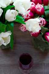 bouquet of beautiful spring flowers, white and red tulips, one glass of aromatic red wine. Woman day.	