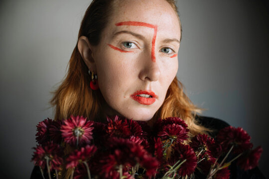Woman with red lipstick marks on face against gray background