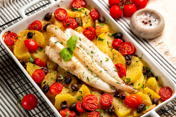 Oven baked anglerfish, monkfish with potato, olives, parsley and tomatoes. Cooked fish dinner in a...