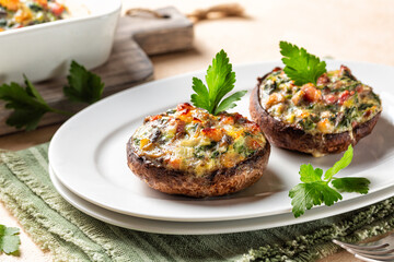 Homemade appetizer stuffed portobello mushrooms cups on a white plate,  stuffed with leek, spinach,...