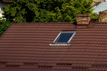 Roof of a new home. Ceramic chimney, metal roof tiles, gutters, roof window. Single family house