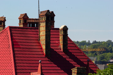 red brick chimney in the top of the village house. A roof made of tiles on the background of the sky