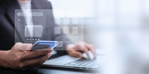 Document management system concept, Businessman using a laptop computer and smartphone at the office after being set up by an IT specialist. Software for corporate file archiving