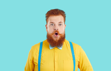 Amazed chubby bearded man with funny surprised expression on light blue background. Stylish...