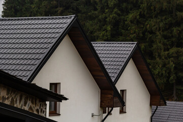 House with new brown metal tile roof and rain gutter. Metallic Guttering System, Guttering and Drainage Pipe Exterior