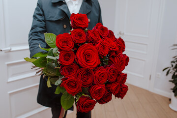 Teenage boy holding bouquet of roses at home