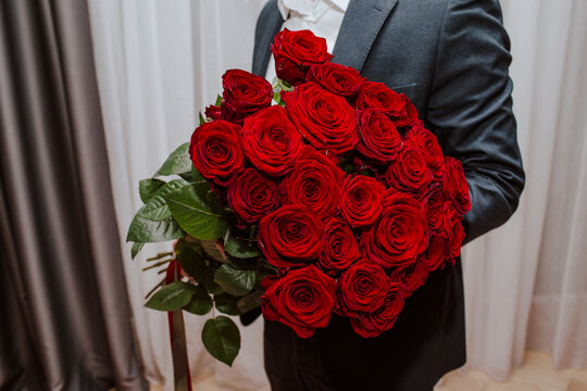 Teenage boy holding bouquet of red roses at home - Powered by Adobe