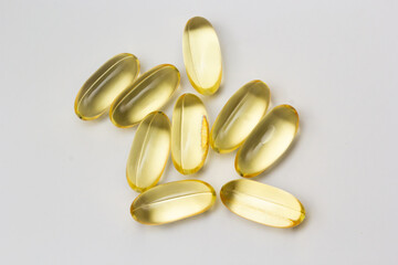 Fish oil capsules omega 3 on light background. Transparent yellow capsules of fish oil
