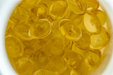 lots of yellow gelatin capsules on a light background. omega viramins, close-up, macro