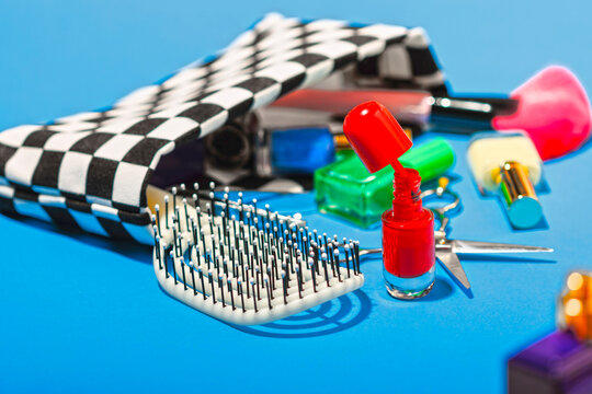 Studio shot of various cosmetics falling out of checked purse
