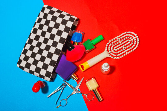 Studio shot of various cosmetics falling out of checked purse