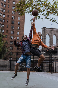 Happy friends slam dunking basketball at court