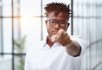 Naklejka premium businessman in glasses pointing at you while standing in a modern office